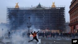 Seorang pengunjuk rasa menendang tabung gas air mata di depan Opera pada akhir unjuk rasa di Paris, Kamis, 23 Maret 2023. (Foto AP/Aurelien Morissard)
