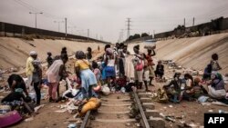 Des marchands ambulants vendent leurs produits sur un marché improvisé en face d'une voie ferrée dans le quartier de Viana à Luanda, le 22 août 2017.