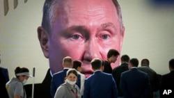 FILE - Participants watch as Russian President Vladimir Putin addresses a plenary session of the St. Petersburg International Economic Forum in St. Petersburg, Russia, June 17, 2022.