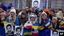 People holding Ukrainian and Polish flags wait for Ukrainian President Volodymyr Zelenskyy during his visit to Warsaw, Poland, April 5, 2023.