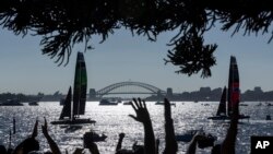 People cheer as Australia SailGP Team and ROCKWOOL Denmark SailGP Team sail past Genesis Island with Sydney Harbour Bridge in the distance on Race Day 2 of the KPMG Australia Sail Grand Prix in Sydney.