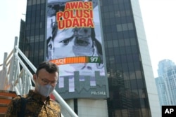 A man walks on a bridge past a billboard that says "Beware of Air Pollution" at the main business district in Jakarta, Indonesia, on Oct. 3, 2023.