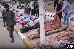 This image grab from footage published on social networks by Libyan al-Masar television channel on Sept. 13, 2023, shows a man inspecting the body of a victim who died in the flooding after Storm Daniel hit Libya's eastern city of Derna. (Photo by Al-Masar TV / AFP)