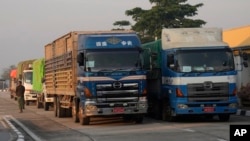 A driver walks by his truck carrying aid before leaving the customs checkpoint near the border with Myanmar, in Mae Sot, Tak province, Thailand, March 25, 2024.