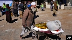 資料照片：2022年2月16日，一名阿富汗男子在喀布爾分發援助物資時用獨輪車運送物資。 （美聯社照片）