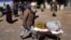FILE - An Afghan man carries supplies in a wheelbarrow during a distribution of aid in Kabul, Feb. 16, 2022. U.S. officials, in recent talks with Taliban leaders, noted data indicating falling inflation and growing trade in Afghanistan in 2023.