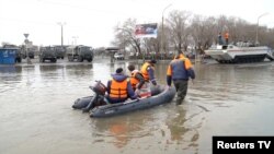Rescuers ride a boat in a flooded street of Orsk, Russia, April 9, 2024, in this still image taken from video. 