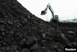 Seorang pekerja mengoperasikan kendaraan berat untuk menurunkan batubara dari tongkang ke truk untuk didistribusikan, di pelabuhan Karya Citra Nusantara di Jakarta Utara, 13 Januari 2022. (REUTERS/Willy Kurniawan)