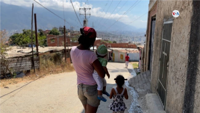 Una mujer lleva a sus hijos a una consulta médica gratuita para evaluar sus pesos y tallas, en Caracas, Venezuela. [Foto: Nicole Kolster]