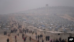 FILE - Syrians walk along in a refugee camp for displaced people run by the Turkish Red Crescent in Sarmada district, north of Idlib city, Syria, on Nov. 26, 2021.