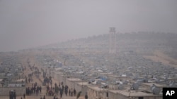 FILE - Syrians walk along in a refugee camp for displaced people run by the Turkish Red Crescent in Sarmada district, north of Idlib city, Syria, on Nov. 26, 2021.