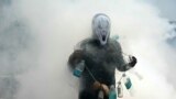 A man wears plastic bottles to spread awareness about mosquito-borne diseases while municipal workers fumigate a locality in Chennai.