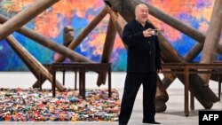 Chinese artist Ai Weiwei takes pictures in front of his pieces displayed during the press preview for the exhibition "Ai Weiwei: Making Sense" at the Design Museum, in London, April 4, 2023.