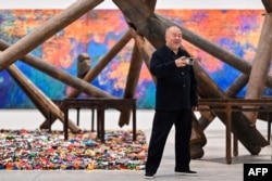 FILE - Chinese artist Ai Weiwei takes pictures in front of his pieces displayed during the press preview for the exhibition "Ai Weiwei: Making Sense" at the Design Museum in London, April 4, 2023.