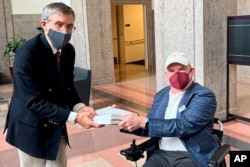 Dan Tate, R, delivers petitions from ALS community to Dr. Peter Marks of the Food and Drug Administration in Silver Spring, Md., on Dec. 14, 2022. (Sonya Elling/I AM ALS via AP)
