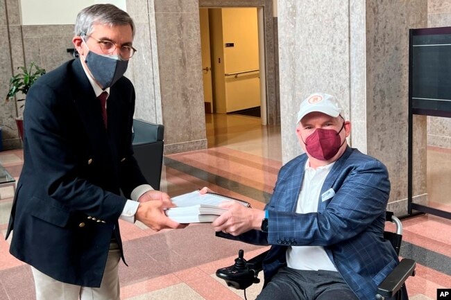 Dan Tate, R, delivers petitions from ALS community to Dr. Peter Marks of the Food and Drug Administration in Silver Spring, Md., on Dec. 14, 2022. (Sonya Elling/I AM ALS via AP)