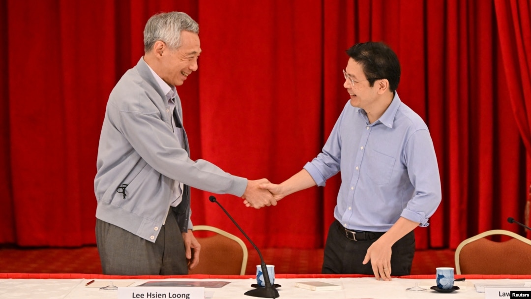 Perdana Menteri Singapura Lee Hsien Loong berjabat tangan dengan Menteri Keuangan Lawrence Wong di Singapura, 16 April 2022. (Foto: SPH Media/The Straits Times/Lim Yaohui via REUTERS) 