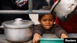 A Palestinian child waits to receive food cooked by a charity kitchen amid shortages of food supplies in Rafah, a city in the southern Gaza Strip, on February 13, 2024. (Ibraheem Abu Mustafa/Reuters)