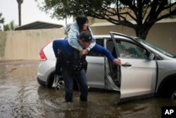 Santa Barbara Police Department detective Bryce Ford helps a motorist out of her car on a flooded street during a rainstorm in Santa Barbara, California, Dec. 21, 2023.
