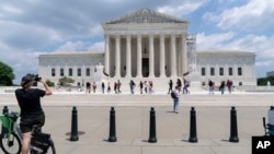 FILE - Visitors pose for photographs in front the U.S. Supreme Court building in Washington, June 18, 2024.