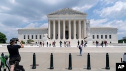 Visitors pose for photographs at the U.S. Supreme Court, June 18, 2024, in Washington. The Supreme Court has sided with the Biden administration in a dispute with Republican-led states over how far the federal government can go to combat controversial social media posts.