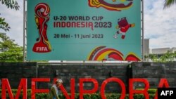 Seorang pria berjalan melewati poster turnamen sepak bola Piala Dunia FIFA U-20 Indonesia 2023 di Jakarta, 30 Maret 2023. FIFA mencoret Indonesia sebagai tuan rumah Piala Dunia U-20 tahun ini di tengah gejolak politik atas partisipasi Israel. (BAY ISMOYO / AFP)