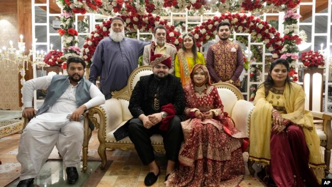 Groom Asher Khan and bride Dua Khan pose for a photo with family members during their wedding at Radiance hall in Karachi, Pakistan, Jan. 27, 2024.