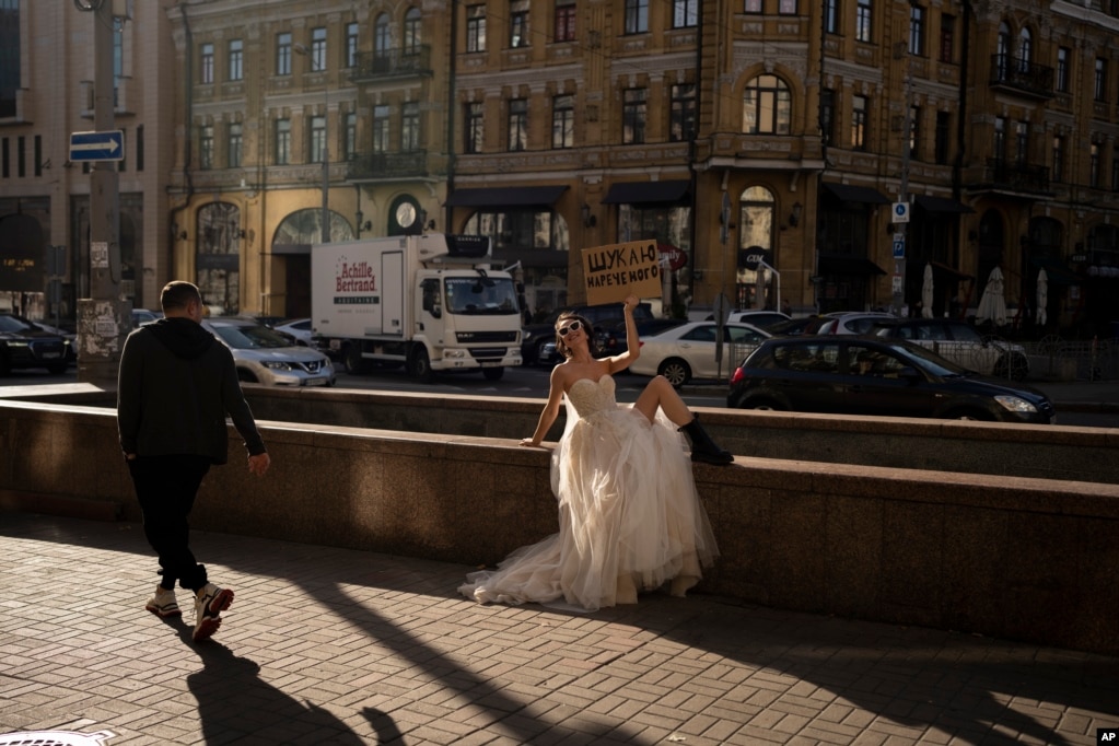 Una mujer posa para una campaña en redes sociales en Kiev, Ucrania, el 31 de octubre de 2023. El cartel dice "Buscando un novio". (AP Foto/Bram Janssen).