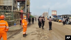 FILE - Police and workers stand near the site of a furnace blast at a PT Indonesia Tsingshan Stainless Steel smelting plant in Morowali, Central Sulawesi, Indonesia, Dec. 24, 2023. Two Chinese nationals on Feb. 12, 2024, were named suspects in the blast.