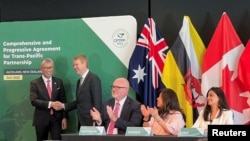 New Zealand PM Hipkins shakes hands with Malaysian Minister of Investment, Trade and Industry Tengku Abdul Aziz, as Britain signs the treaty to join the Comprehensive and Progressive Agreement for Trans-Pacific Partnership, in Auckland, July 16, 2023.