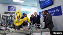 FILE - President Joe Biden and others listen as an industrial systems student at Nash Community College in Rocky Mount, N.C., demonstrates how a robot arm can move, June 9, 2023. 