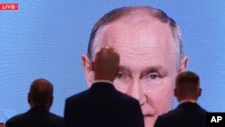 La gente mira una pantalla de televisión que transmite el discurso del presidente ruso, Vladimir Putin, en la sesión plenaria del Foro Económico y Humanitario Rusia-África en San Petersburgo, Rusia, el jueves 27 de julio de 2023. (TASS Host Photo Agency Pool Photo vía AP)