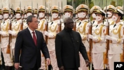FILE - Visiting Solomon Islands Prime Minister Manasseh Sogavare, right, and his Chinese counterpart Li Qiang review an honor guard during a welcome ceremony at the Great Hall of the People in Beijing, July 10, 2023.