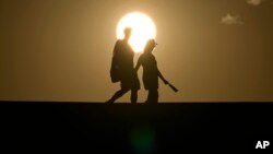 ক্যালিফোর্নিয়ার ডেথ ভ্যালি ন্যাশনাল পার্কের মধ্য দিয়ে মানুষ হেঁটে যাচ্ছে। ১৬ জুলাই, ২০২৩।