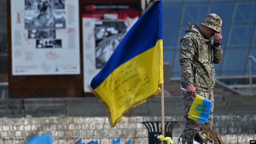Seorang prajurit tampak berduka di samping bendera Ukraina pada peringatan bagi tentara yang gugur di Lapangan Kemerdekaan di Kyiv, 10 November 2023. (Foto: AFP)