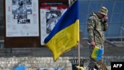 Seorang prajurit tampak berduka di samping bendera Ukraina pada peringatan bagi tentara yang gugur di Lapangan Kemerdekaan di Kyiv, 10 November 2023. (Foto: AFP)