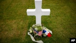 An American flag, left, and French flag lay at headstones in the American Cemetery in Colleville-sur-Mer, Normandy, June 5, 2023.