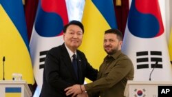 South Korean President Yoon Suk Yeol, left, and Ukrainian President Volodymyr Zelenskyy stand for photos after delivering statements, July 15, 2023, in Kyiv, Ukraine.