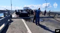 Investigators work on the automobile span of the Crimean Bridge connecting Russian mainland with Crimea after traffic on the bridge was halted July 17, 2023, after reports of explosions, which Russia blamed on Ukraine. (Investigative Committee of Russia via AP)