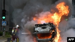 FILE - A firefighter extinguishes a burning car at the end of a commemoration march for a teenage driver shot dead by a policeman, in the Parisian suburb of Nanterre, France, June 29, 2023.