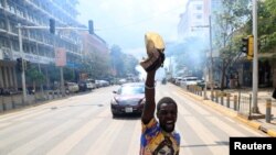 An activists reacts after riot police officers lobbed teargas canisters to disperse them, during a march to call on lawmakers to reject the finance bill proposed by the government that would raise taxes across the economy, along Harambee avenue in downtown Nairobi, Kenya.&nbsp;