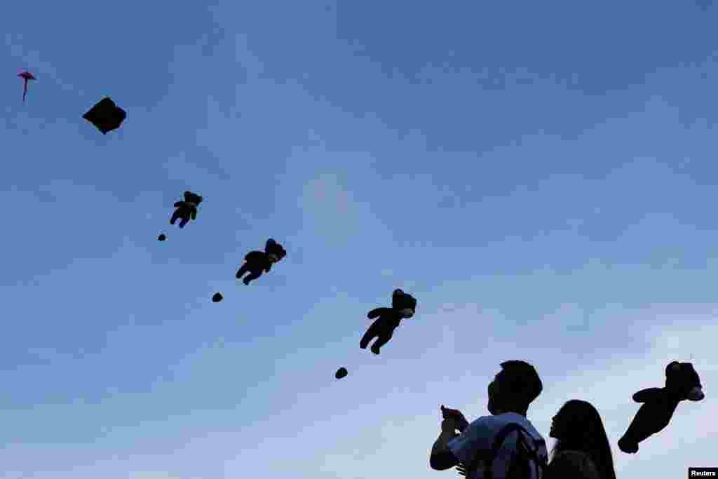 A couple fly kites during a kite festival at a department store in Bangkok, Thailand.