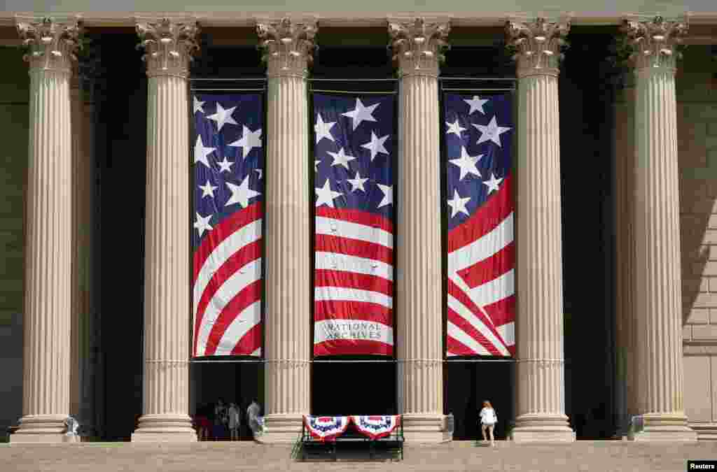 A woman climbs the steps to the flag-decorated National Archives, home of the Declaration of Independence, a day before the Fourth of July holiday,&nbsp;in Washington, July 3, 2023.