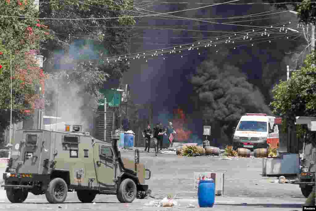 Palestinians run during clashes with Israeli forces amid an Israeli military operation in Jenin, in the Israeli-occupied West Bank.