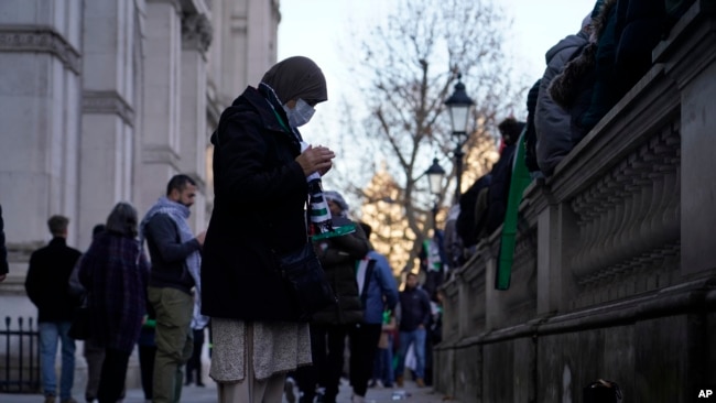 A woman prays on the route as she takes part in a pro-Palestinian demonstration as they wend their way along Whitehall in London, Nov. 25, 2023.