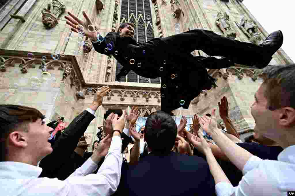 A newly ordered Catholic priest celebrates with friends and relatives outside the Duomo Cathedral, in Milan, Italy, after the ordination ceremony, June 10, 2023. 