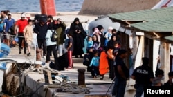 پناهجویان در حال پیاده شدن از یک کشتی در لامپدوسا – سیسیلی، ایتالیا. ۲۷ شهریور ۱۴۰۲ – عکس از رویترز