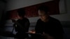 FILE - Wang Quanzhang and his wife, Li Wenzu, look at their phone and laptop in the dark after power was cut off for their apartment in Beijing's Changping district, June 20, 2023.