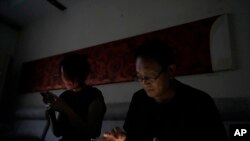 资料照片：中国律师王全璋与妻子李文足在黑暗中查看手机，他们在北京的住所电力被当局切断（2023年6月20日）