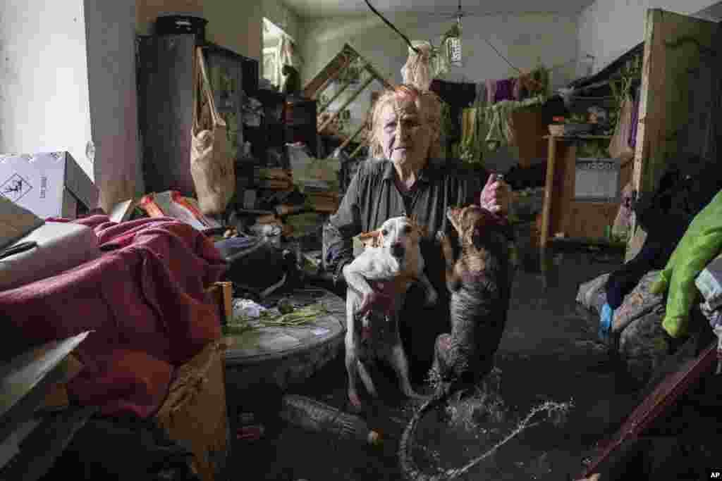 Una mujer sostiene a sus mascotas en su vivienda inundada tras el derrumbe de la represa de Kajovka, en Jersón, Ucrania, el 6 de junio de 2023. (AP Foto/Evgeniy Maloletka).